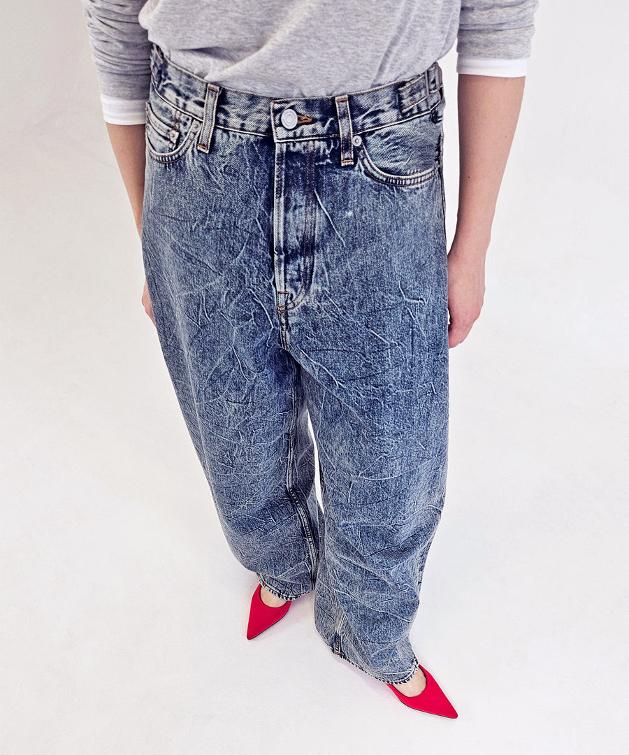 A model posting with MONLE Red pointed-toe pump, styled with crinkled blue denim wide pants and simple grey+white long sleeve top