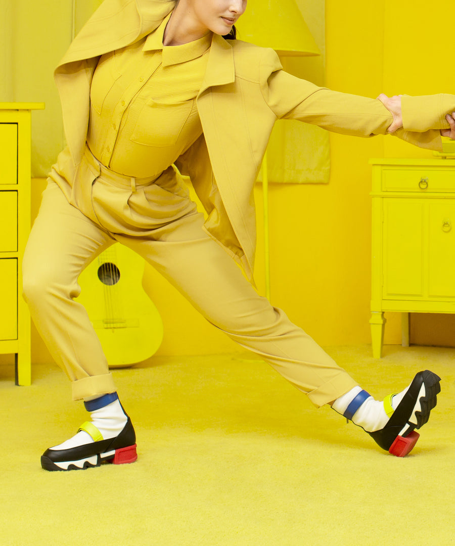 A dancing model wearing VES Multi Primary High Top Sneaker with all yellow two-piece suit