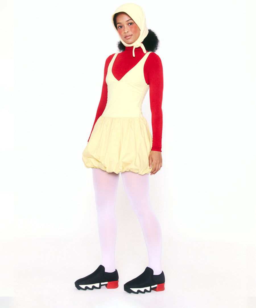 A model wearing WES Black Red Neoprene Sneaker with puffy yellow dress, red turtle neck top and matching yellow balaclava hat