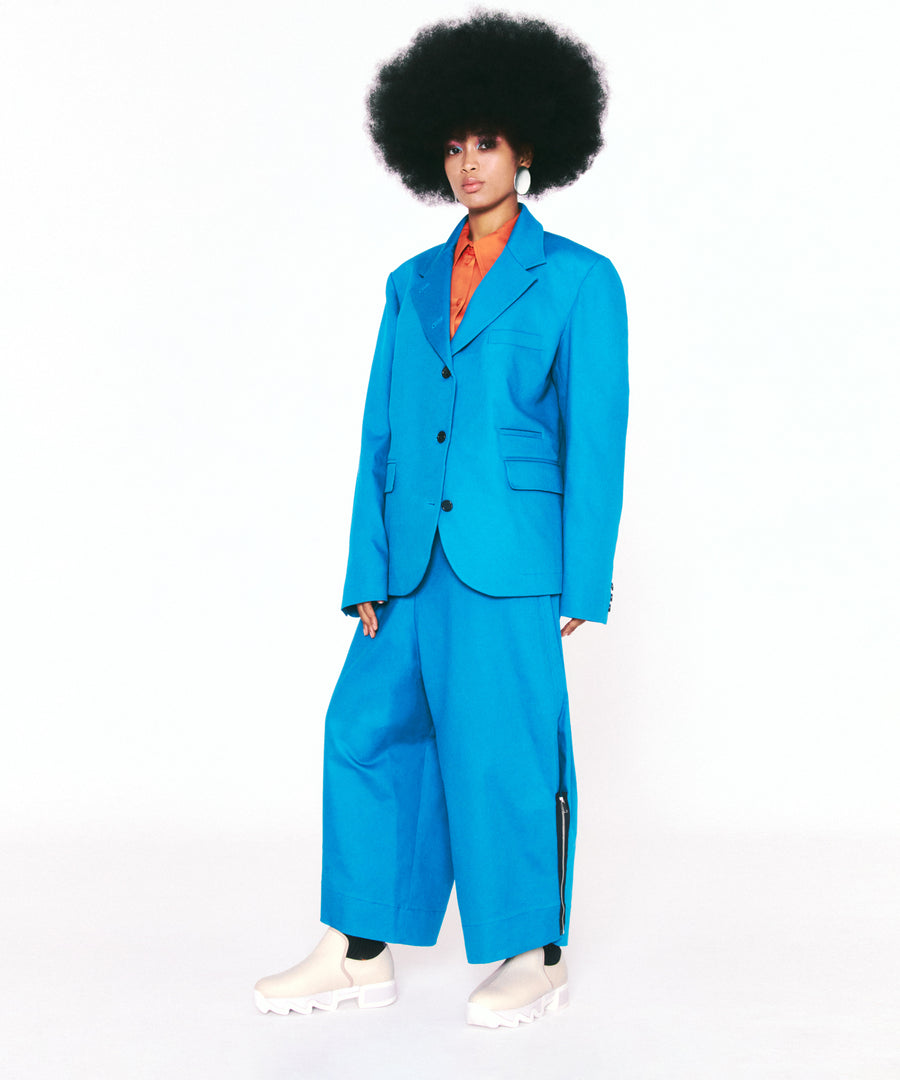 A black model wearing matching cyan blue suit paired with WES III Sand Low Top Sneaker in her natural afro hair